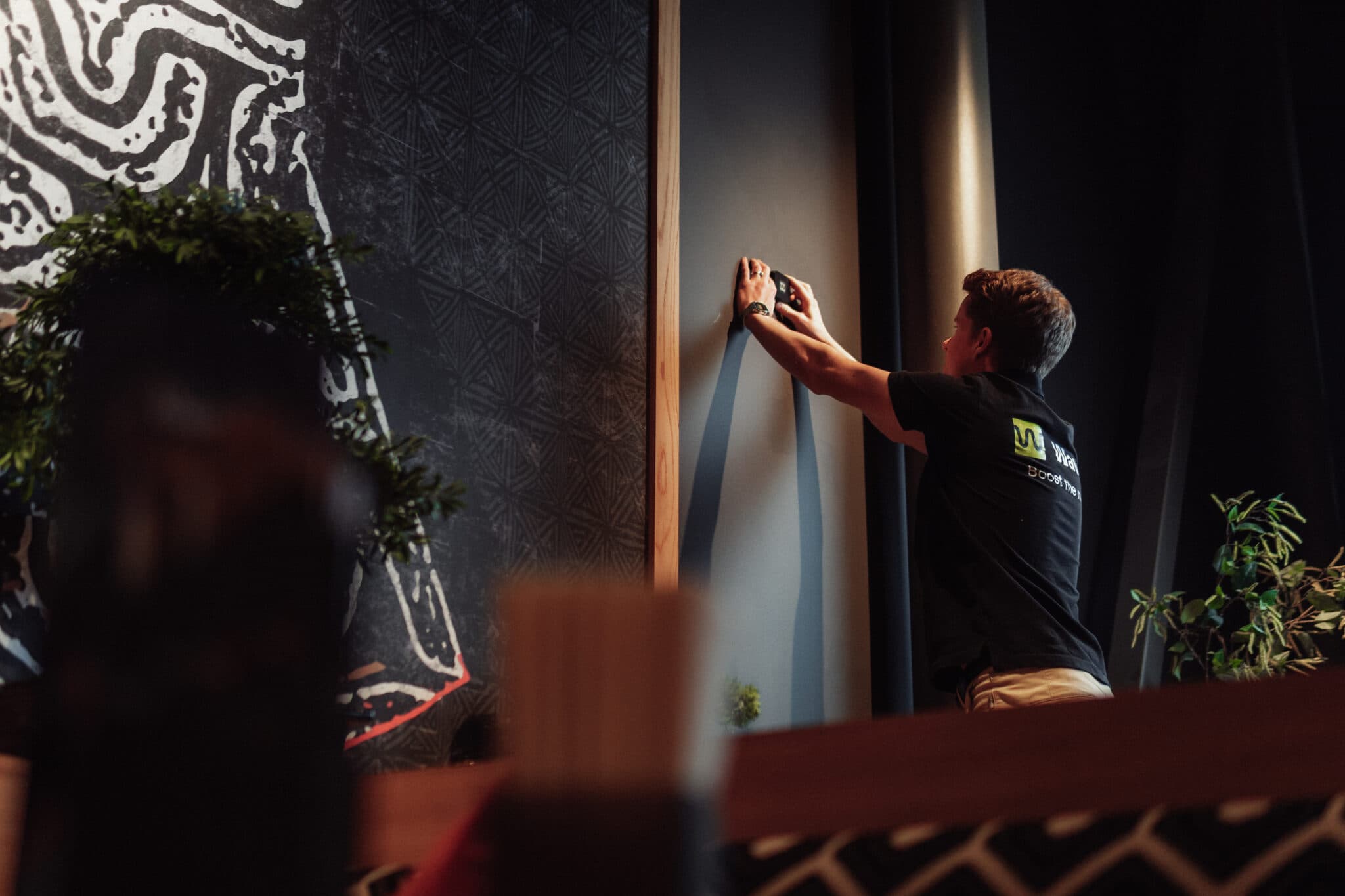 A Waved employee mounting a sensor on a wall in a restaurant