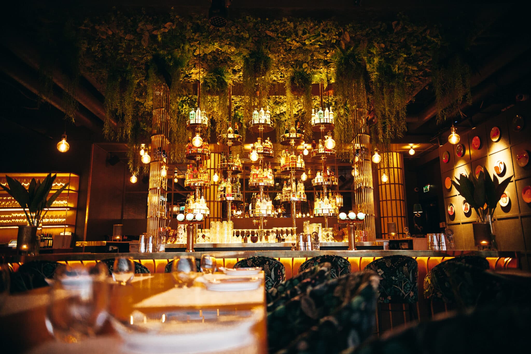 A bar at night, lit warm, with guests seated along the counter